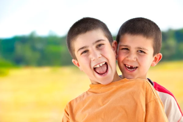 Bonito engraçado jovem sorrindo irmãos jogar ao ar livre no campo — Fotografia de Stock