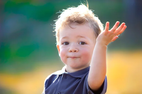 Feliz niño sonriente jugando con diente de león al aire libre en un jardín —  Fotos de Stock