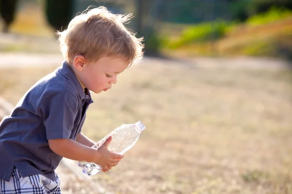 Beautiful blonde child drink water outdoor — Stock Photo, Image