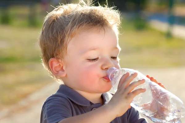 Beautiful blonde child drink water outdoor — Stock Photo, Image