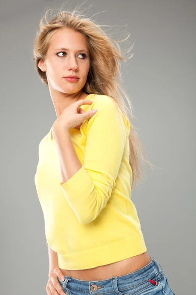 Красивая блондинка улыбается девушка с желтой футболкой изолированы на сером — стоковое фото