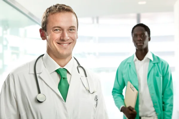 Bello sorridente bionda medico con nero uomo infermiera a ospedale — Foto Stock