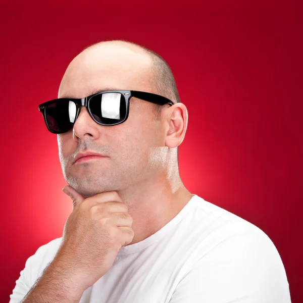 Hombre calvo con gafas de sol sobre fondo rojo —  Fotos de Stock