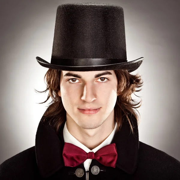 Joven con sombrero de copa y retrato de pajarita sobre fondo gris — Foto de Stock