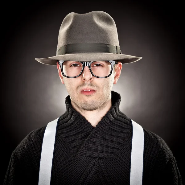 Hombre joven nerd con sombrero y gafas sobre fondo negro — Foto de Stock