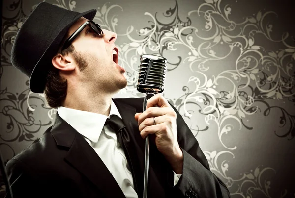 Funny vintage singer with microphone portrait in a tapestry background — Stock Photo, Image