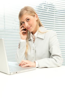 dizüstü konuşma telefonda yakınındaki jaluzi pencere ile sarışın iş kadını gülümseyen