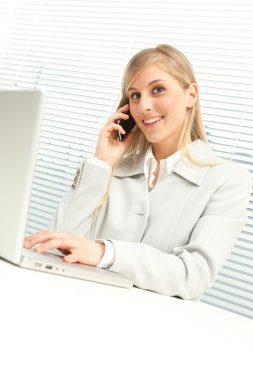 dizüstü konuşma telefonda yakınındaki jaluzi pencere ile sarışın iş kadını gülümseyen