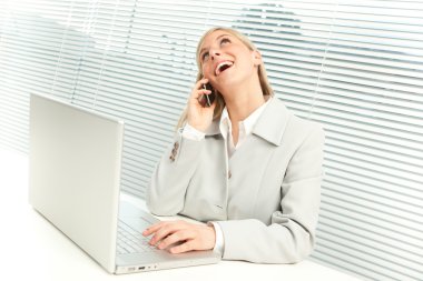 dizüstü konuşma telefonda yakınındaki jaluzi pencere ile sarışın iş kadını gülümseyen