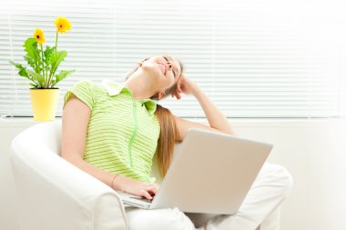 Genç güzel kadın laptop oturma odasında jaluzi pencere ile çalışmak