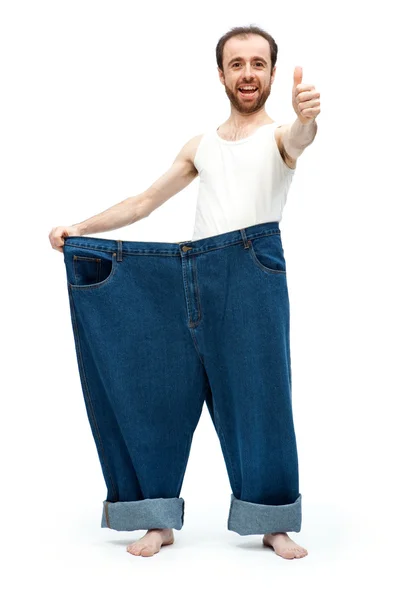 Legrační štíhlý muž s velkými kalhoty džíny izolovaných na bílém — Stock fotografie