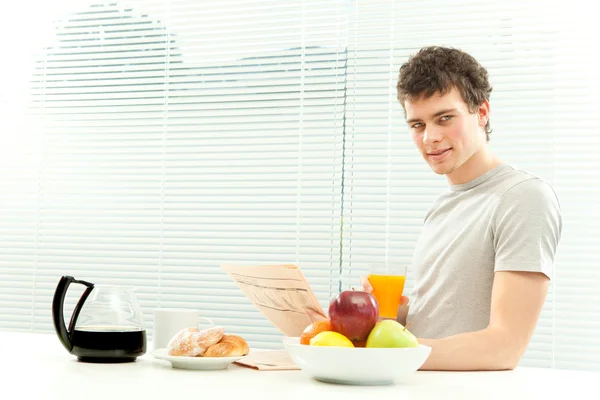 Curly young man have breakfast read newspaper with venetian blind window — Stock Photo, Image