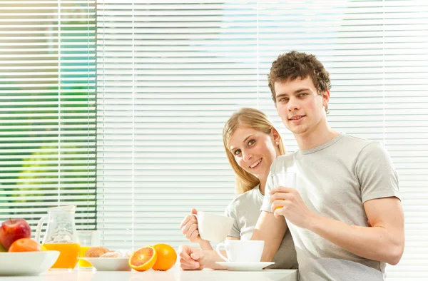 Young casual couple have breakfast with coffee and fruit with venetian blind window — Stock Photo, Image