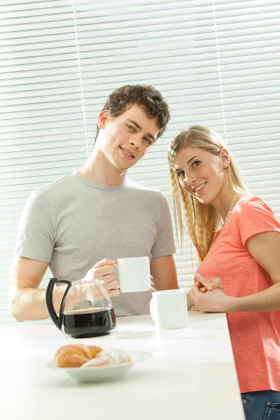 Young casual couple have breakfast with coffee and croissant with venetian blind window — Stock Photo, Image