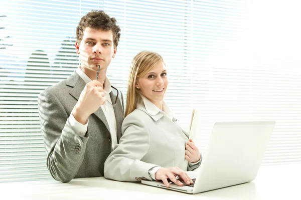 Giovane business coppia di lavoro laptop con veneziana finestra cieca sfondo — Foto Stock