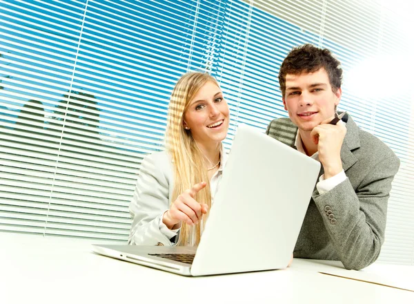 Giovane business coppia di lavoro laptop con veneziana finestra cieca sfondo — Foto Stock