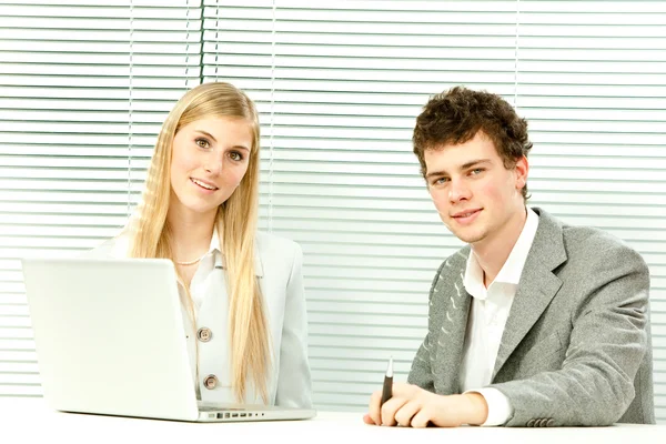 Giovane business coppia di lavoro laptop con veneziana finestra cieca sfondo — Foto Stock