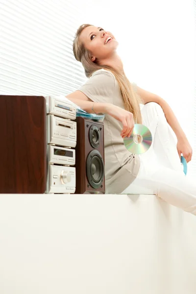 Junge schöne Frau hört Musik mit CD-ROM im Wohnzimmer — Stockfoto