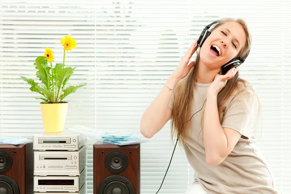 Jovem mulher bonita ouvir música com fone de ouvido em uma sala de estar — Fotografia de Stock