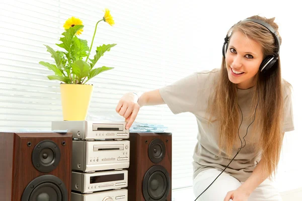 Jovem mulher bonita ouvir música com fone de ouvido em uma sala de estar — Fotografia de Stock