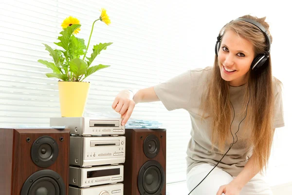 Ung vacker kvinna lyssna på musik med hörlurar i ett vardagsrum — Stockfoto