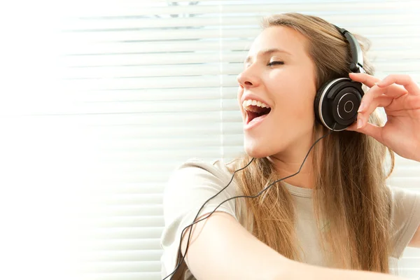 Jovem mulher bonita ouvir música com fone de ouvido em uma sala de estar — Fotografia de Stock