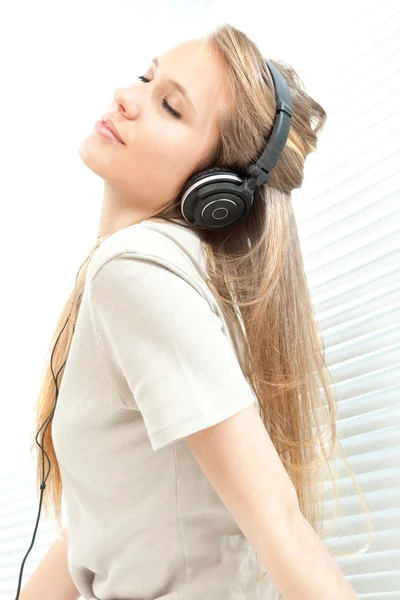 Jovem mulher bonita ouvir música com fone de ouvido em uma sala de estar — Fotografia de Stock