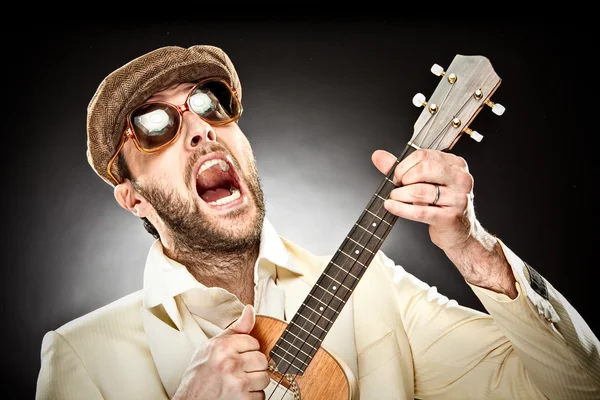 Lustiger Mann mit Brille spielt Gitarre Ukelele auf schwarzem Hintergrund — Stockfoto