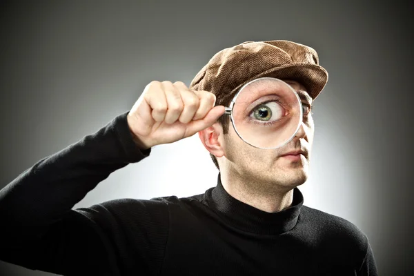 Nieuwsgierig man kijken met Vergrootglas glas op grijze achtergrond — Stockfoto