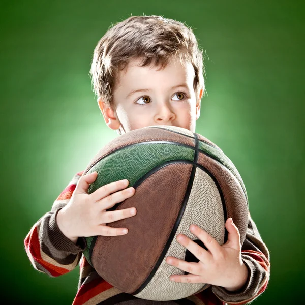 Bonito criança segurar grande cesta bola no fundo verde — Fotografia de Stock