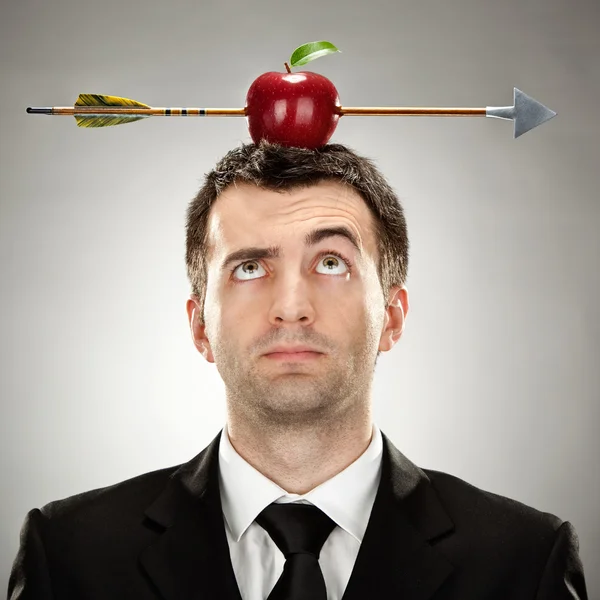 Förvånad affärsman rött äpple på huvudet träffas av pilen på grå bakgrund — Stockfoto