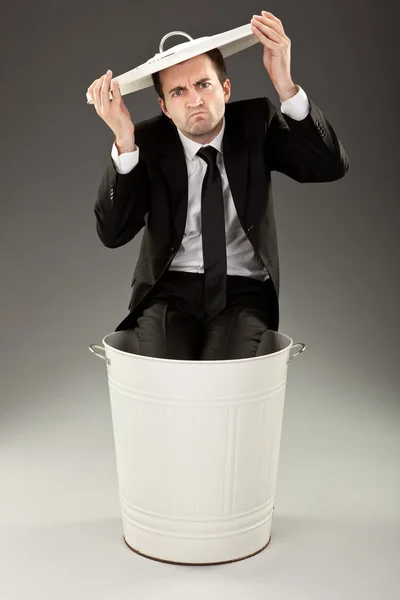 Funny businessman throw out in a bin on grey background — Stock Photo, Image