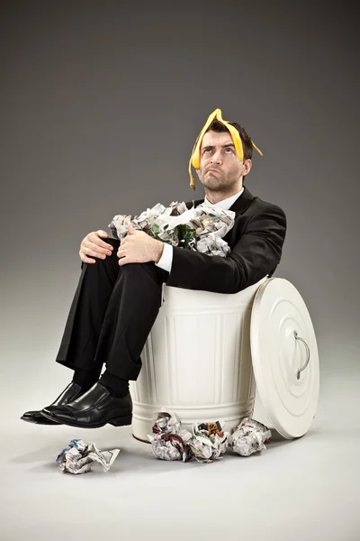 Funny businessman throw out in a bin on grey background — Stock Photo, Image