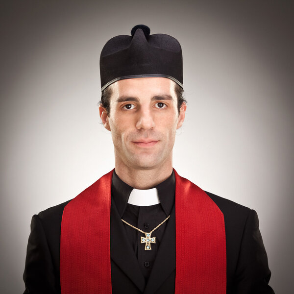 young cristian catholic priest with crucifix smile portrait on grey background