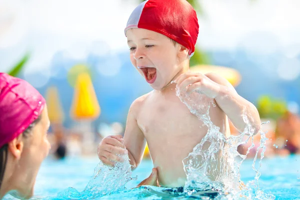 Niño feliz y mamá con gorra de piscina divertirse en una piscina — Foto de Stock