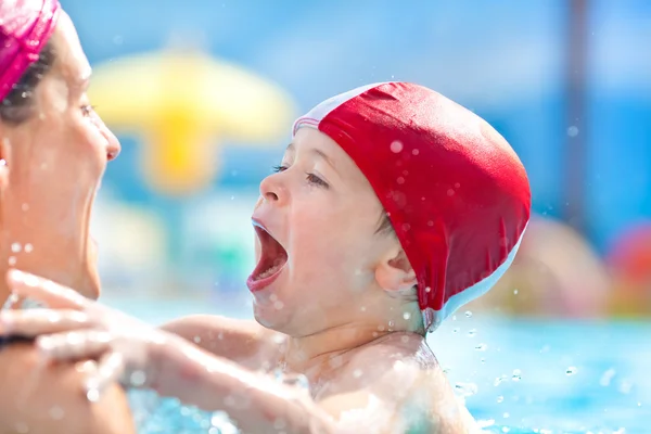 Niño feliz y mamá con gorra de piscina divertirse en una piscina — Foto de Stock