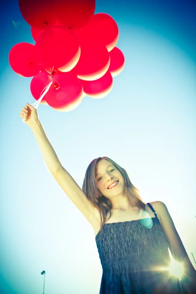 Schönes junges Mädchen mit rotem Ballon an einem sonnigen Tag — Stockfoto