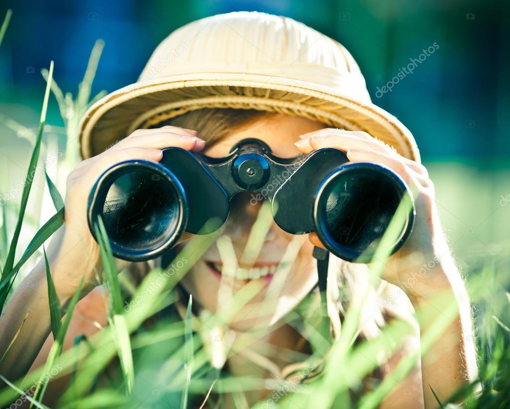 Beautiful young explorer girl with hat and binocular at park Stock