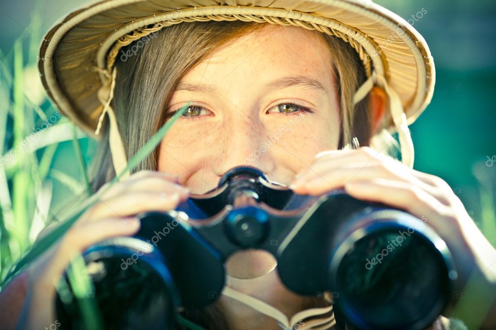 Beautiful young explorer girl with hat and binocular at park Stock
