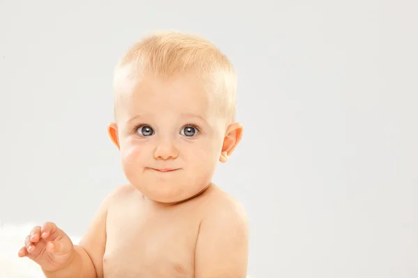 Mooie blonde haren, blauwe ogen baby in een witte kamer — Stockfoto