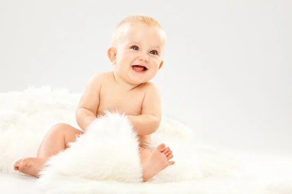 Vackra blonda hår blå ögon baby i ett vitt rum — Stockfoto