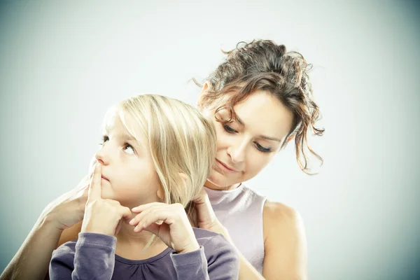 Beautiful brunette woman with young blond girl on grey background — Stock Photo, Image
