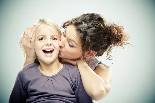 Beautiful brunette woman with young blond girl on grey background — Stock Photo, Image