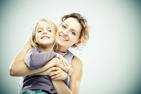 Beautiful brunette woman with young blond girl on grey background — Stock Photo, Image