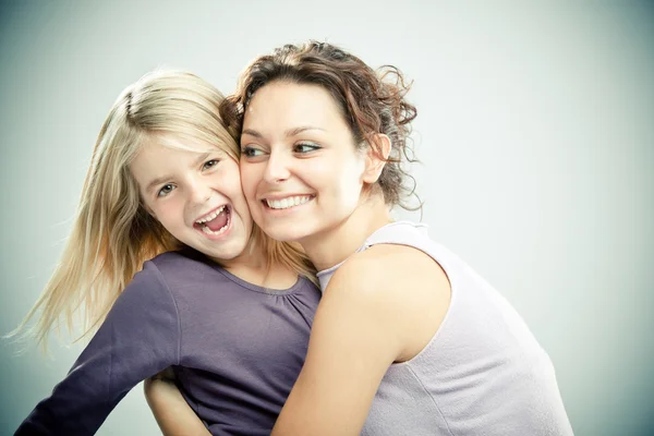 Beautiful brunette woman with young blond girl on grey background — Stock Photo, Image