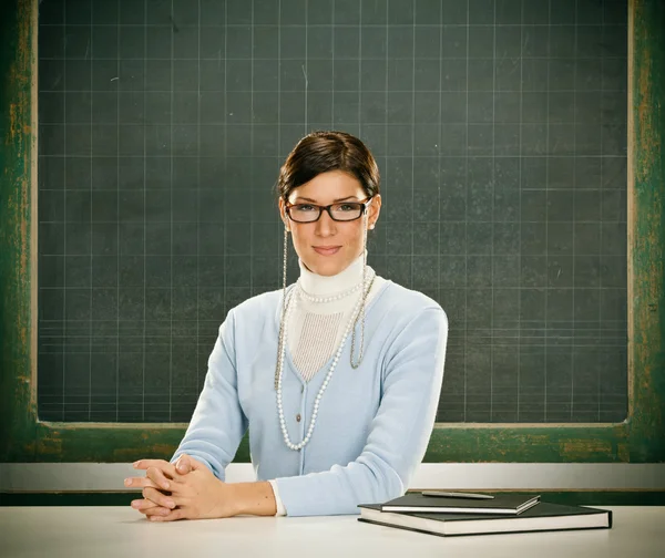 Schöne ernsthafte junge Lehrerin mit Brille und Blackbouard — Stockfoto