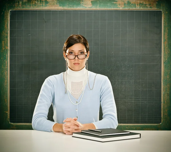 Vackra allvarliga unga lärare med glasögon och blackbouard — Stockfoto