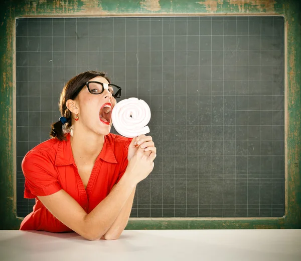 Sensuele jonge student rood gekleed met glazen eten snoep en blackboard — Stockfoto