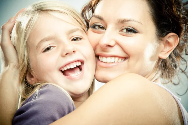 Beautiful brunette woman with young blond girl on grey background Stock Photo
