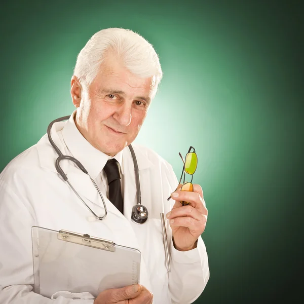 Vecchio medico con occhiali e stetoscopio ritratto isolato su verde — Foto Stock